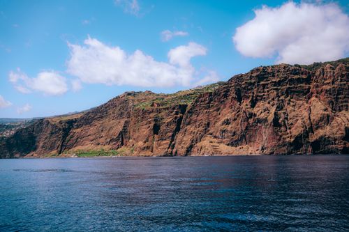 Free Stunning coastal cliff and calm sea under a bright blue sky. Stock Photo