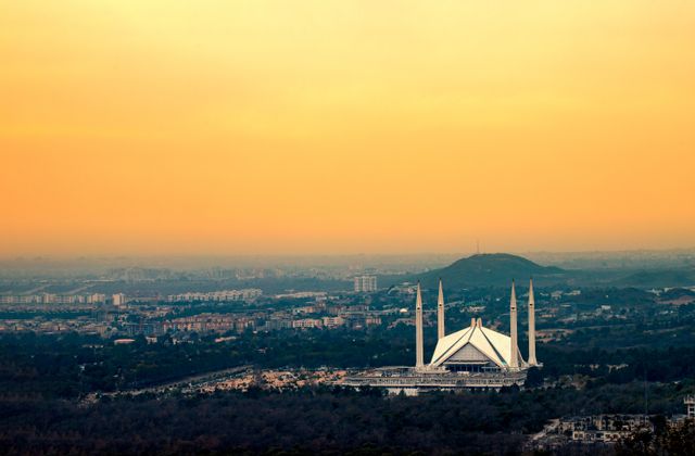Captured from above, Islamabad's Faisal Mosque silhouetted against a vibrant sunset sky. — arriving in Attock