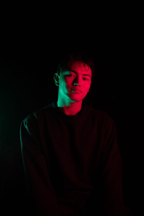 Free Artistic portrait of a man in dramatic neon lighting in a studio setting. Stock Photo