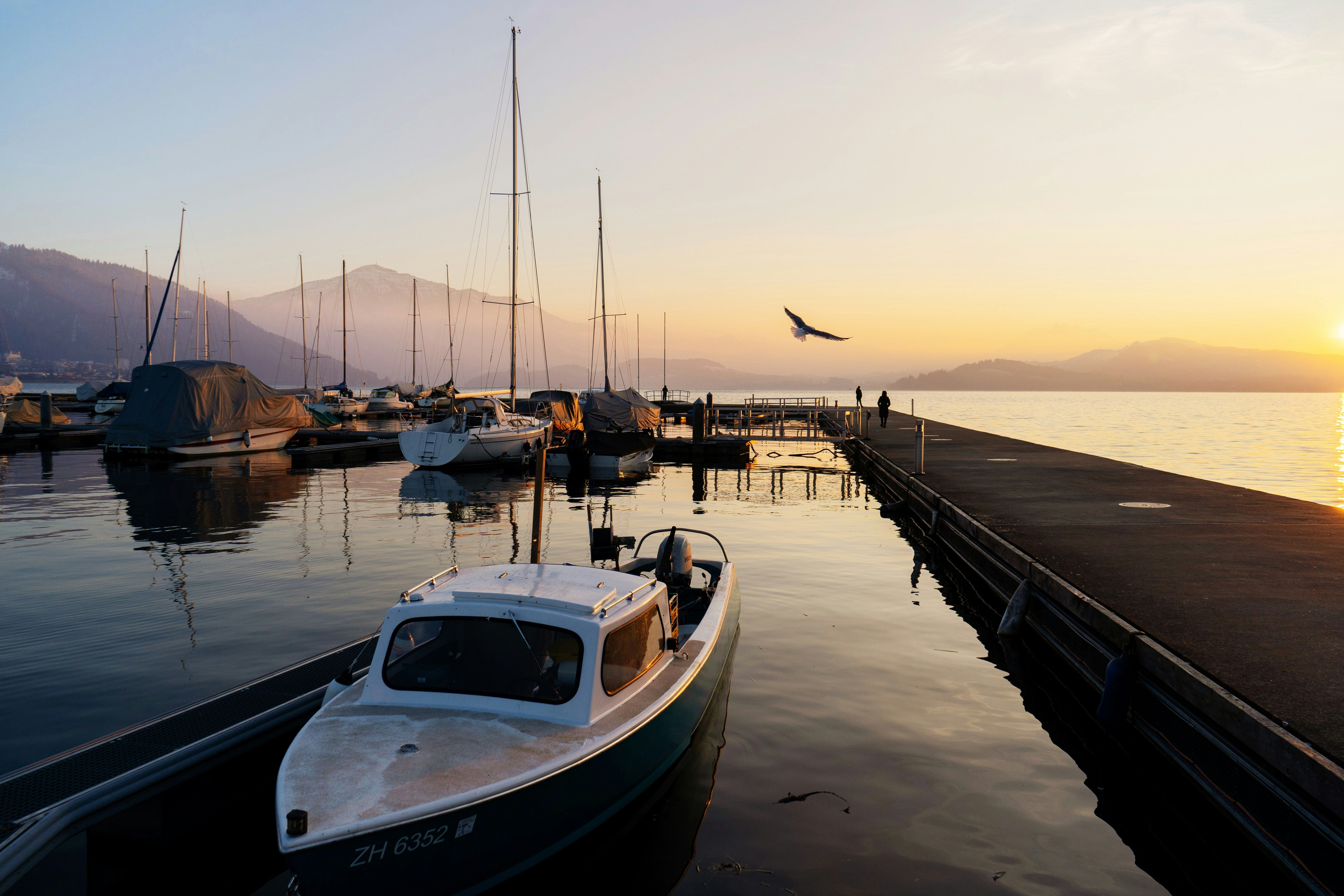A tranquil scene of boats at Zug marina during sunrise, reflecting a peaceful morning.