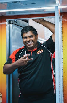 A cheerful man poses for a portrait in a food truck setting, showcasing customer service.