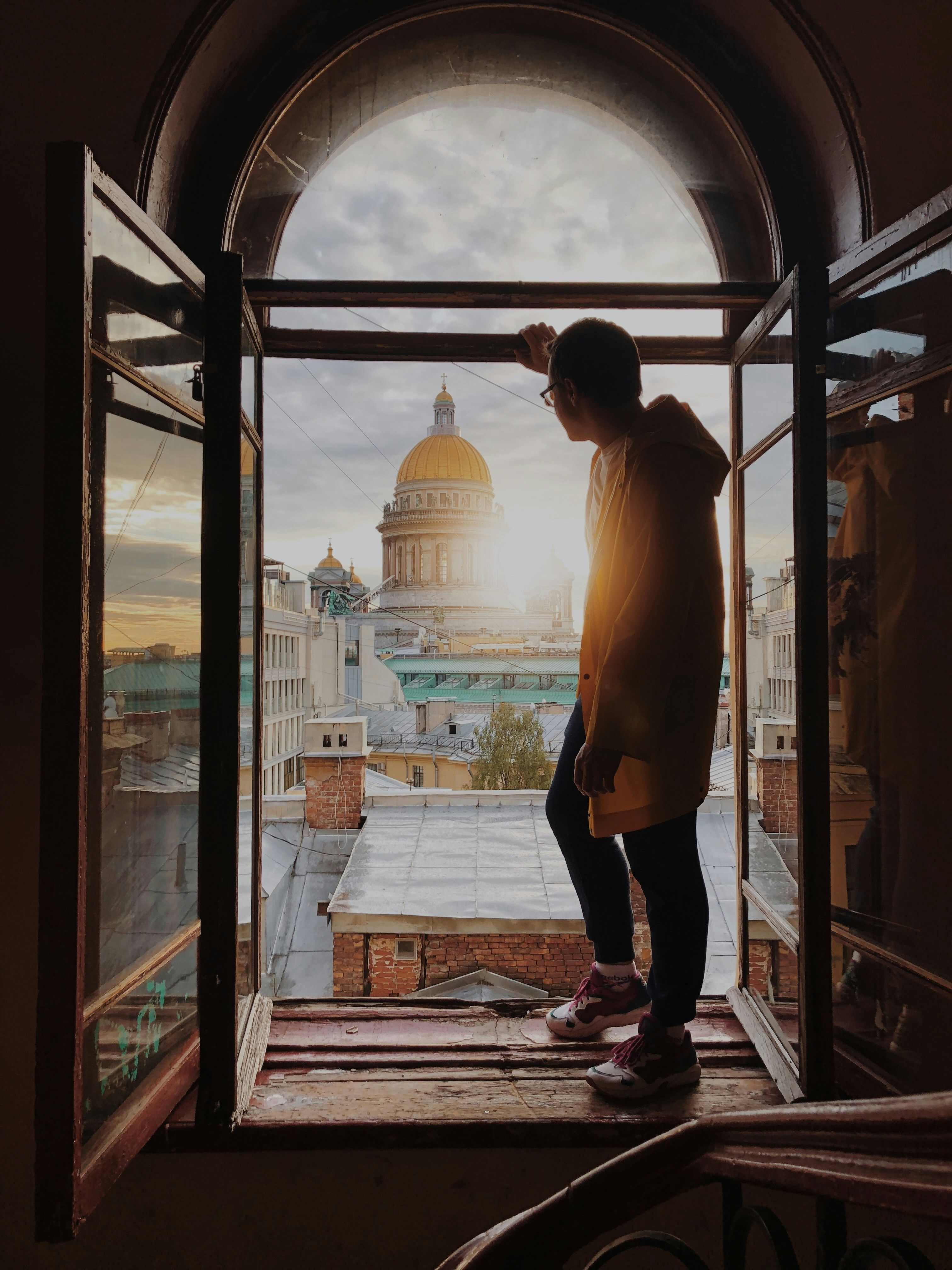 A person looking out of an open window at the city · Free Stock Photo