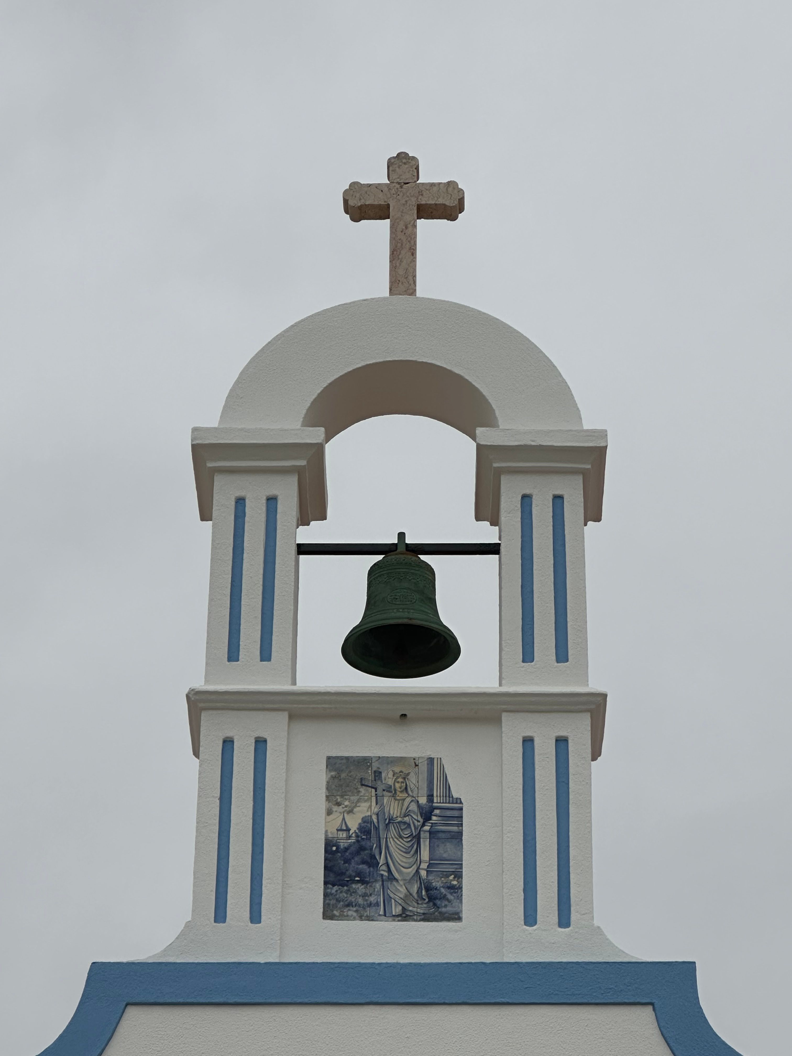 Classic Portuguese chapel with a bell tower in Silveira, Lisboa, featuring a cross and religious tile art.