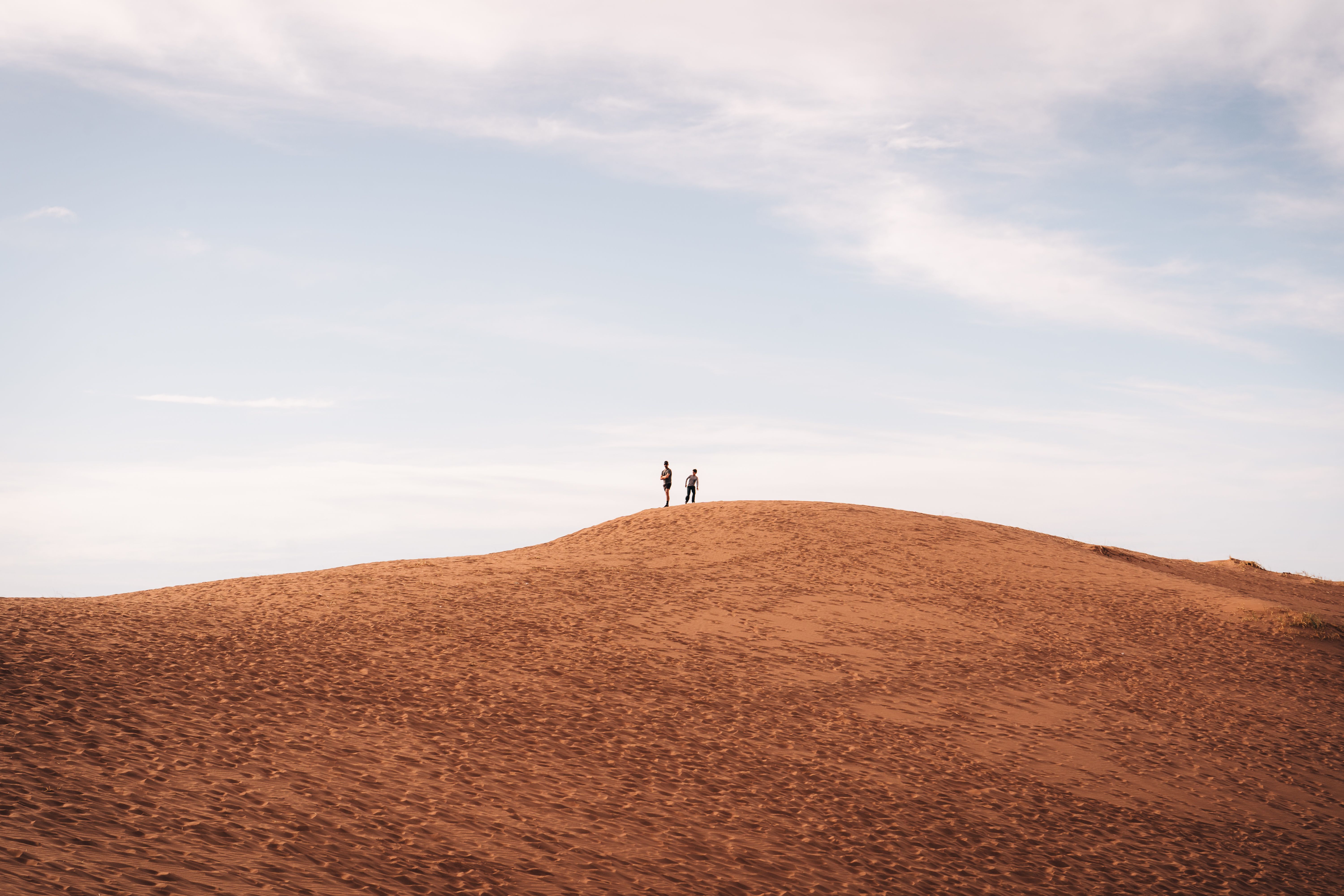 Two people standing on top of a sand dune · Free Stock Photo