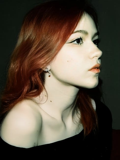 Graceful side profile of a young woman with red hair and off-shoulder attire.