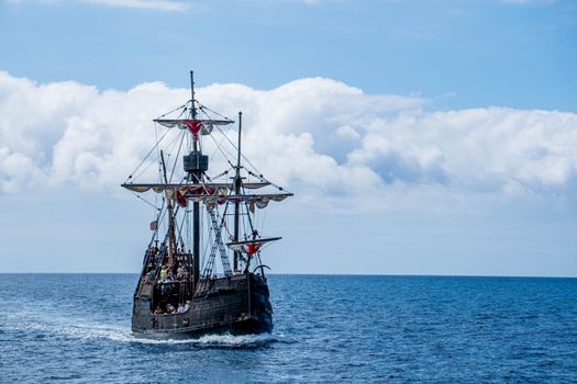 A majestic sailing ship cruises the open sea near Funchal, Madeira.