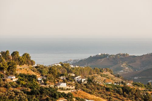 Free Stunning aerial view of Mediterranean coastline with hills and trees under a bright summer sky. Stock Photo