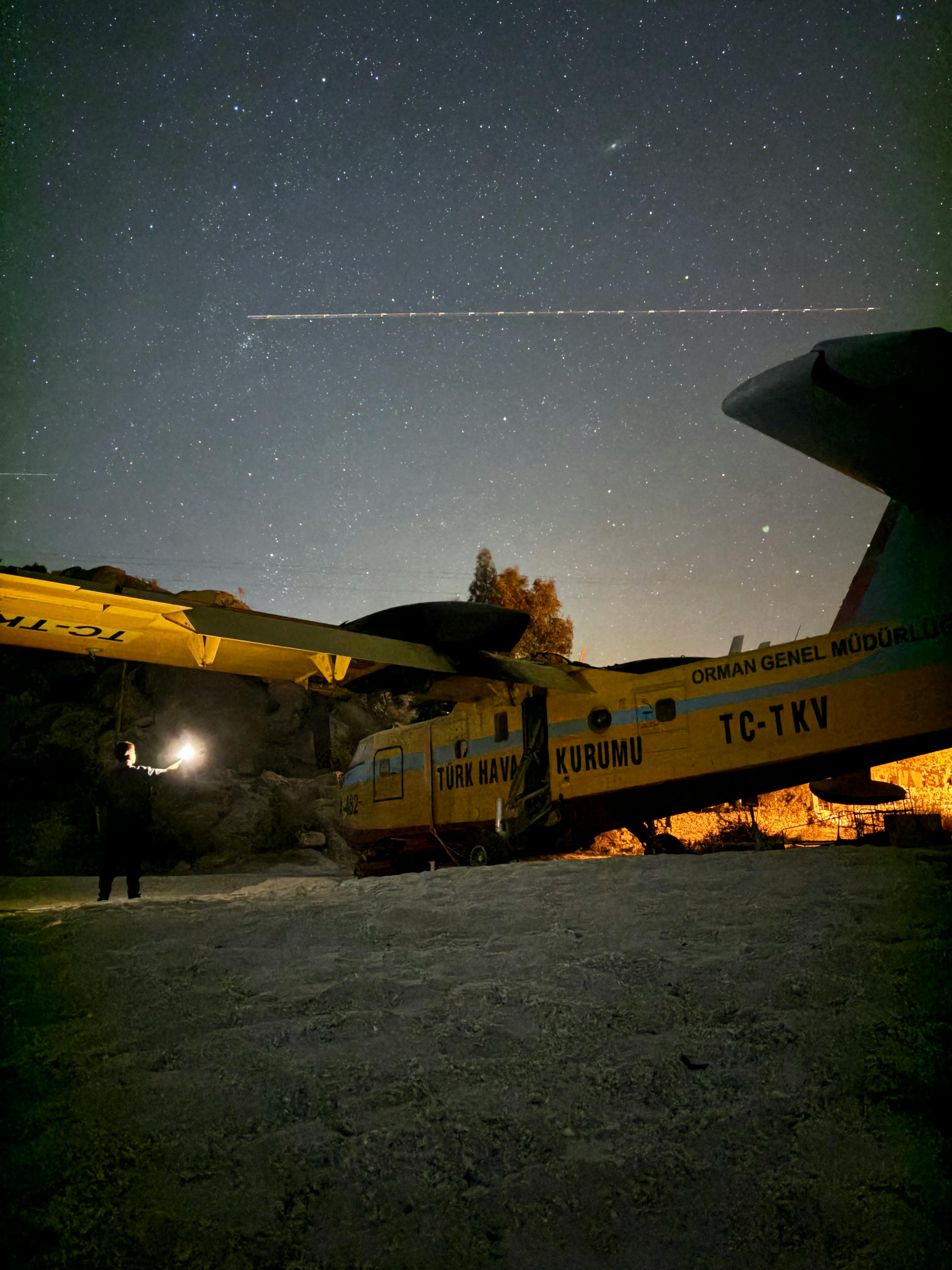 a man standing next to a plane at night