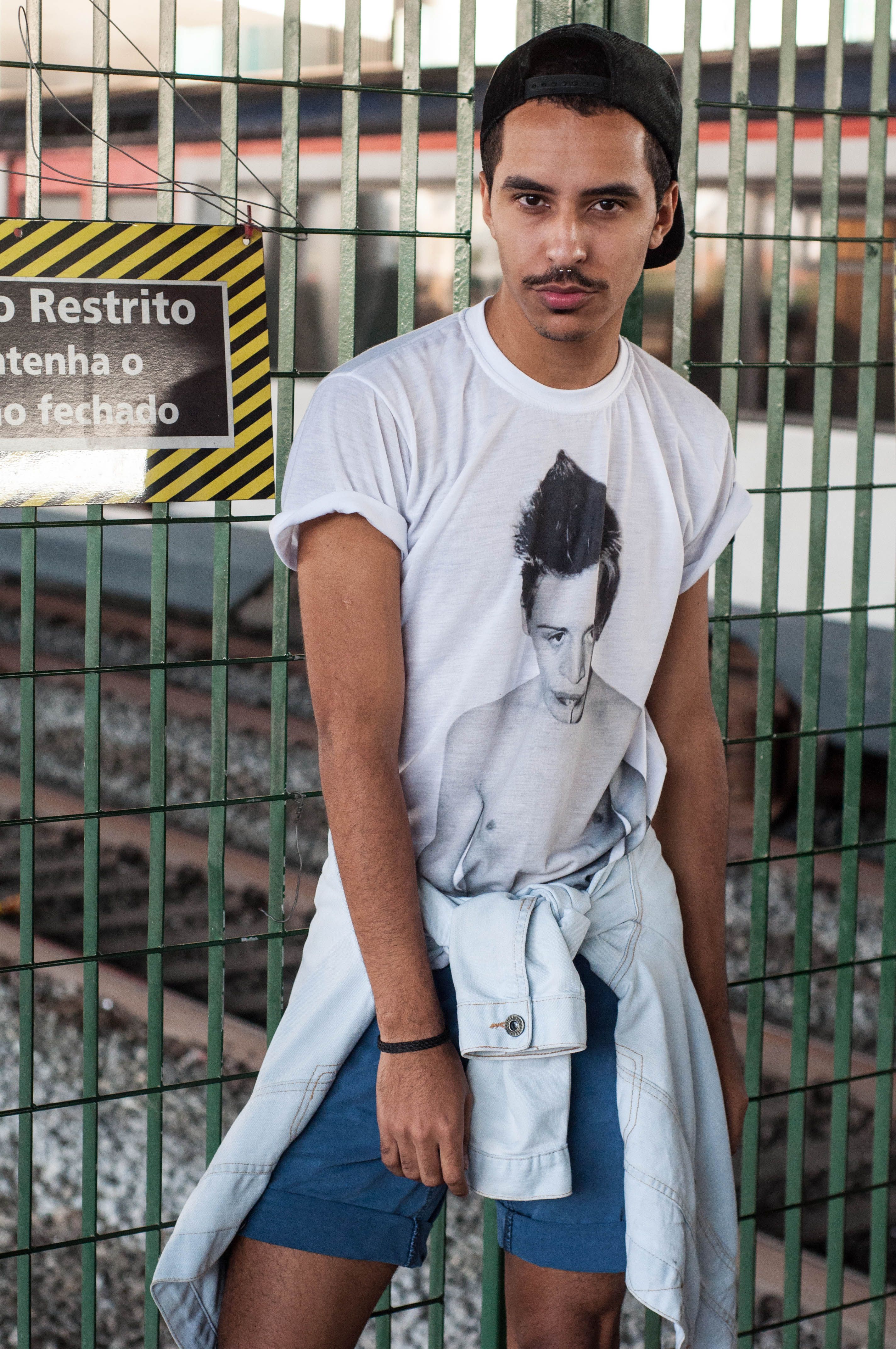 A stylish young man poses outdoors wearing a casual t-shirt and shorts, exemplifying modern urban fashion.