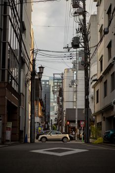 A city street in Kyoto featuring modern architecture and a parked car, highlighting urban life.