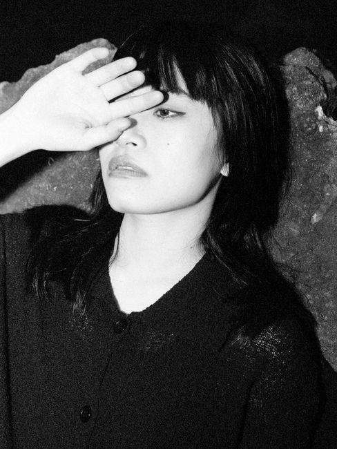 Artistic black and white portrait of a woman shielding her eyes with her hand.