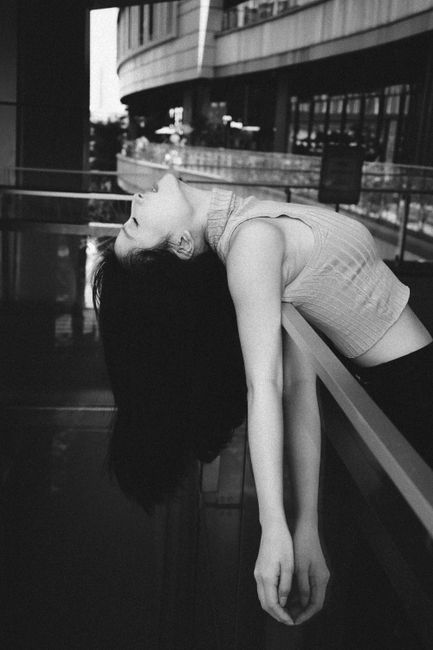 Black and white photo of a woman artistically posed indoors, evoking a dramatic mood.