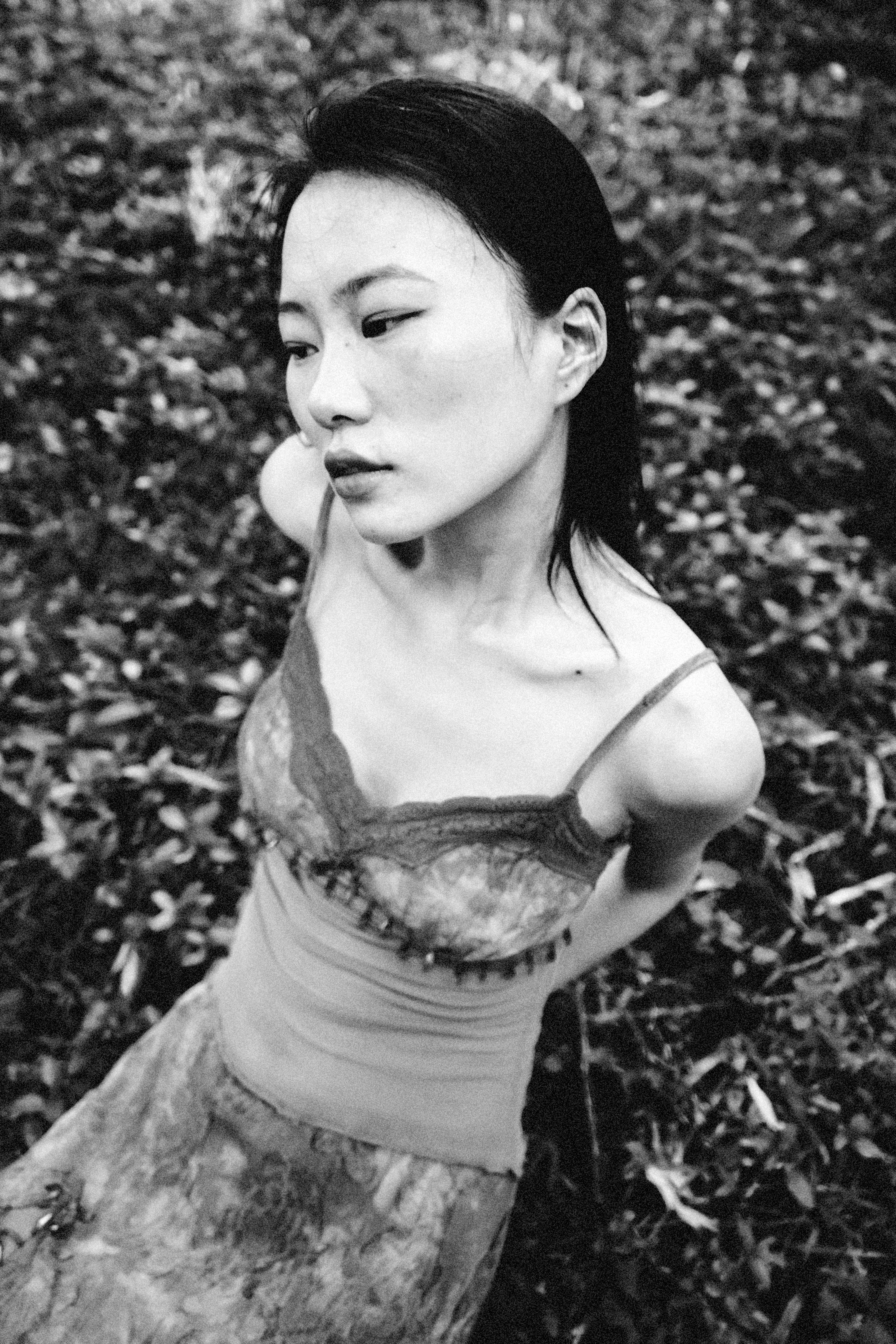 Elegant black and white portrait of a woman posing outdoors in a dress.