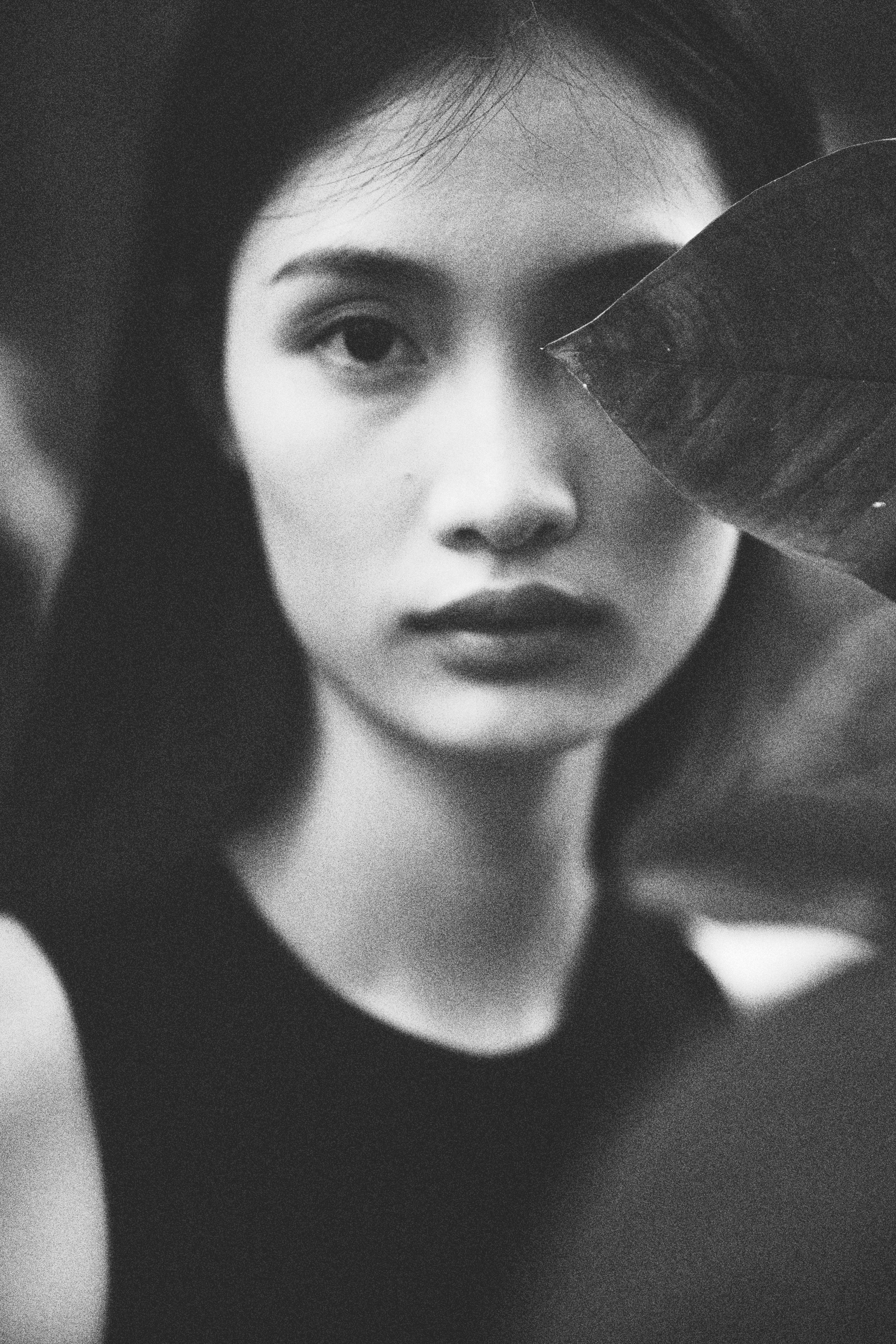 Artistic black and white portrait capturing a woman's contemplative gaze amidst nature.