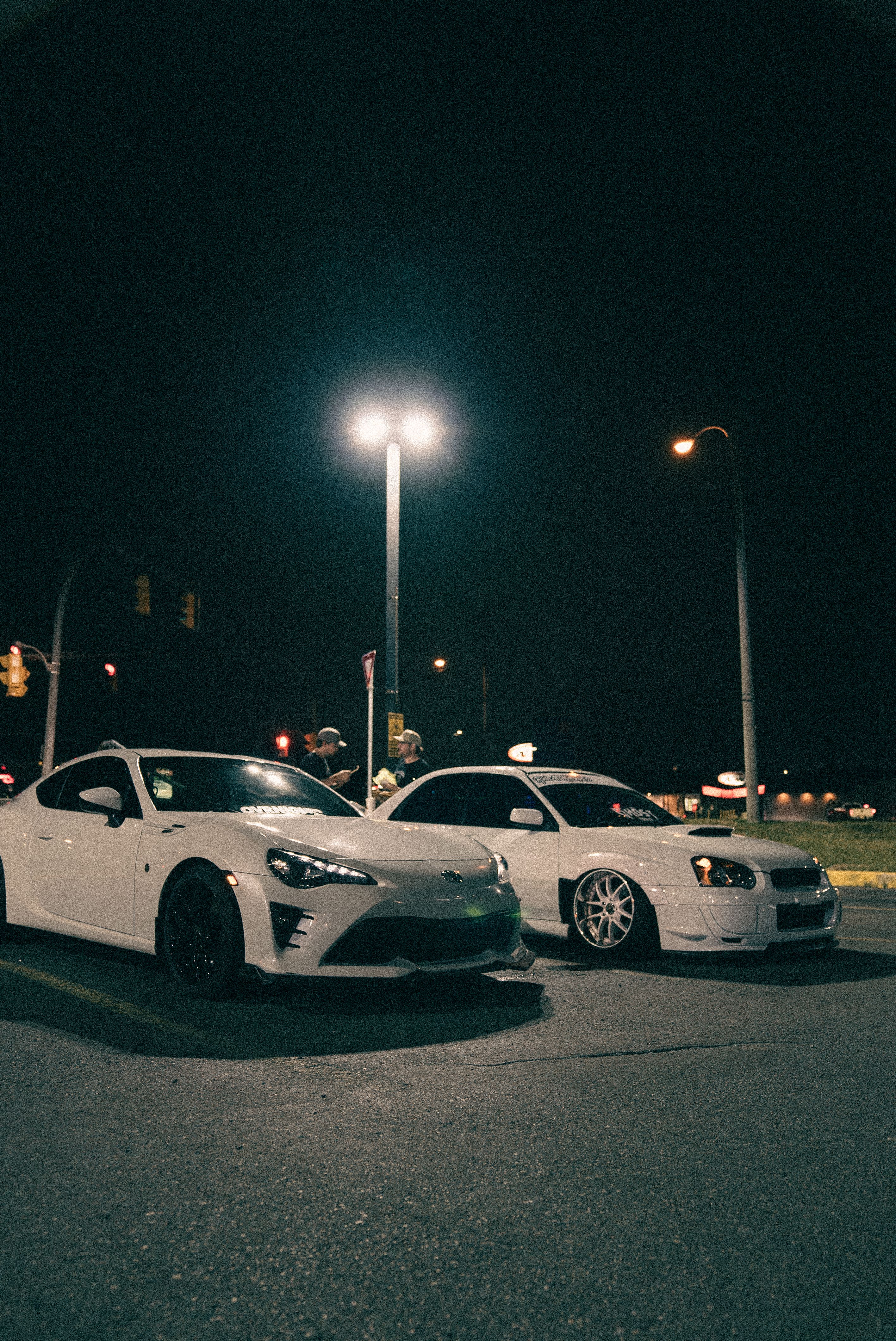 Two white cars parked at night in a parking lot · Free Stock Photo