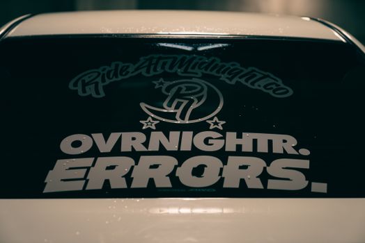 Close-up of a vehicle's back window featuring bold typography decals, emphasizing unique style.