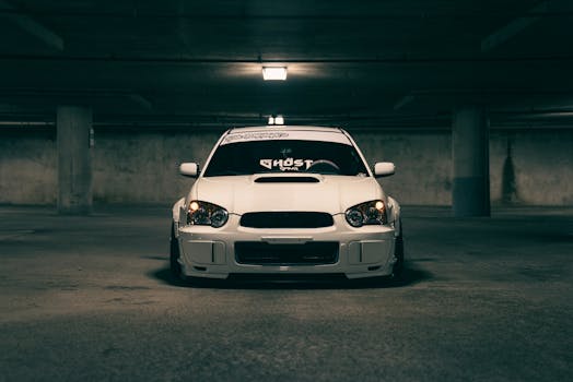 A sleek white sports car sits in a dimly lit underground parking garage, exuding a mysterious appeal.