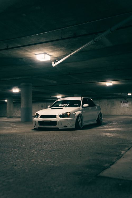 Free White modified car parked in a dimly lit underground garage, showcasing urban automotive scene. Stock Photo