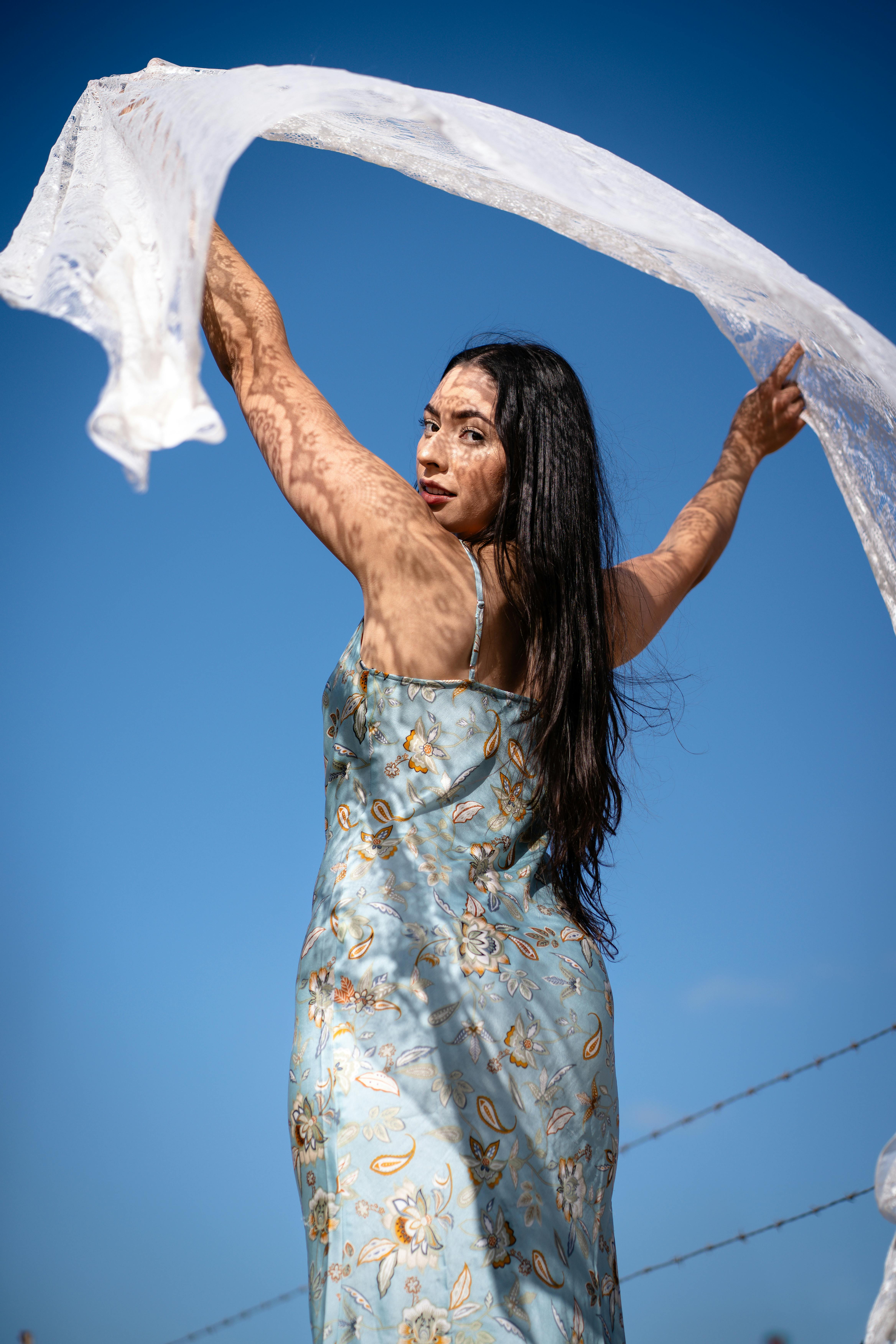 Free A woman in a dress holding up a white sheet Stock Photo