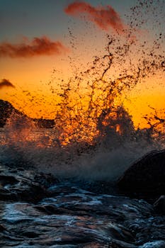 日落充满活力，海浪猛烈撞击岩石，激起强烈的视觉冲击