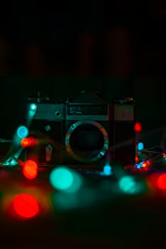 A vintage camera surrounded by vibrant bokeh string lights, creating a warm, nostalgic scene.