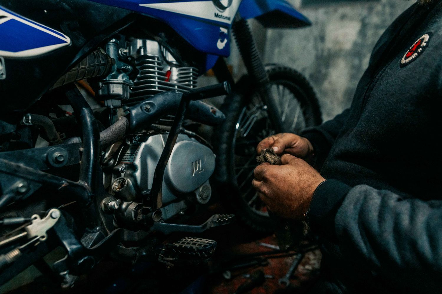 Motocicleta em manutenção dentro de oficina, com foco na parte mecânica