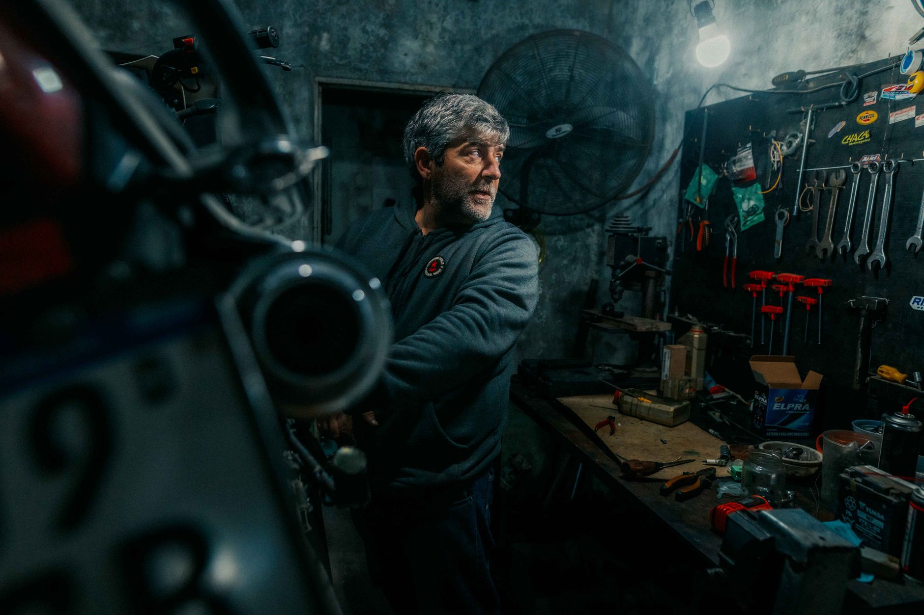 A focused mechanic working in a dimly lit garage, surrounded by tools and machinery.