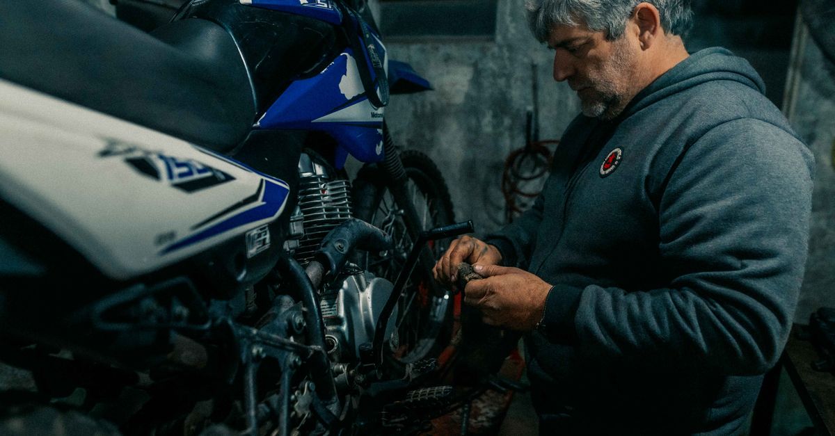 Foto de moto en An adult man repairs a motorcycle in a dimly lit garage, showcasing mechanical expertise. · ServiMotriz Villavicencio