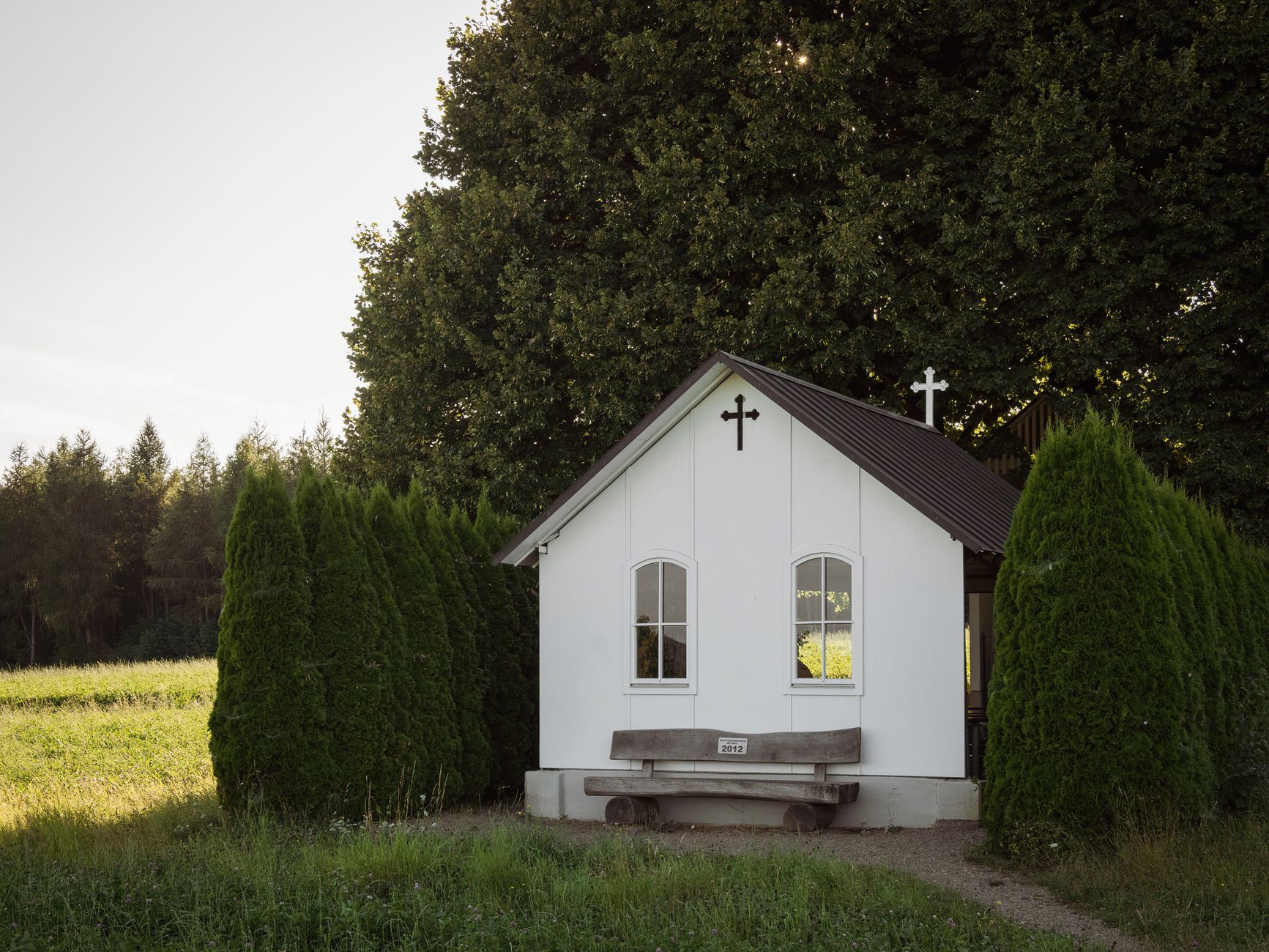 A peaceful small white church nestled among trees and greenery in a rural setting.
