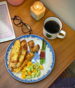 A warm, inviting breakfast with French toast, coffee, and a candle on a wooden table.