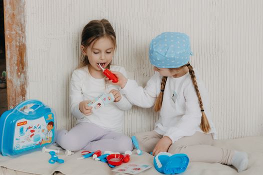 Two children playing dentist at home with a toy set, learning and having fun.