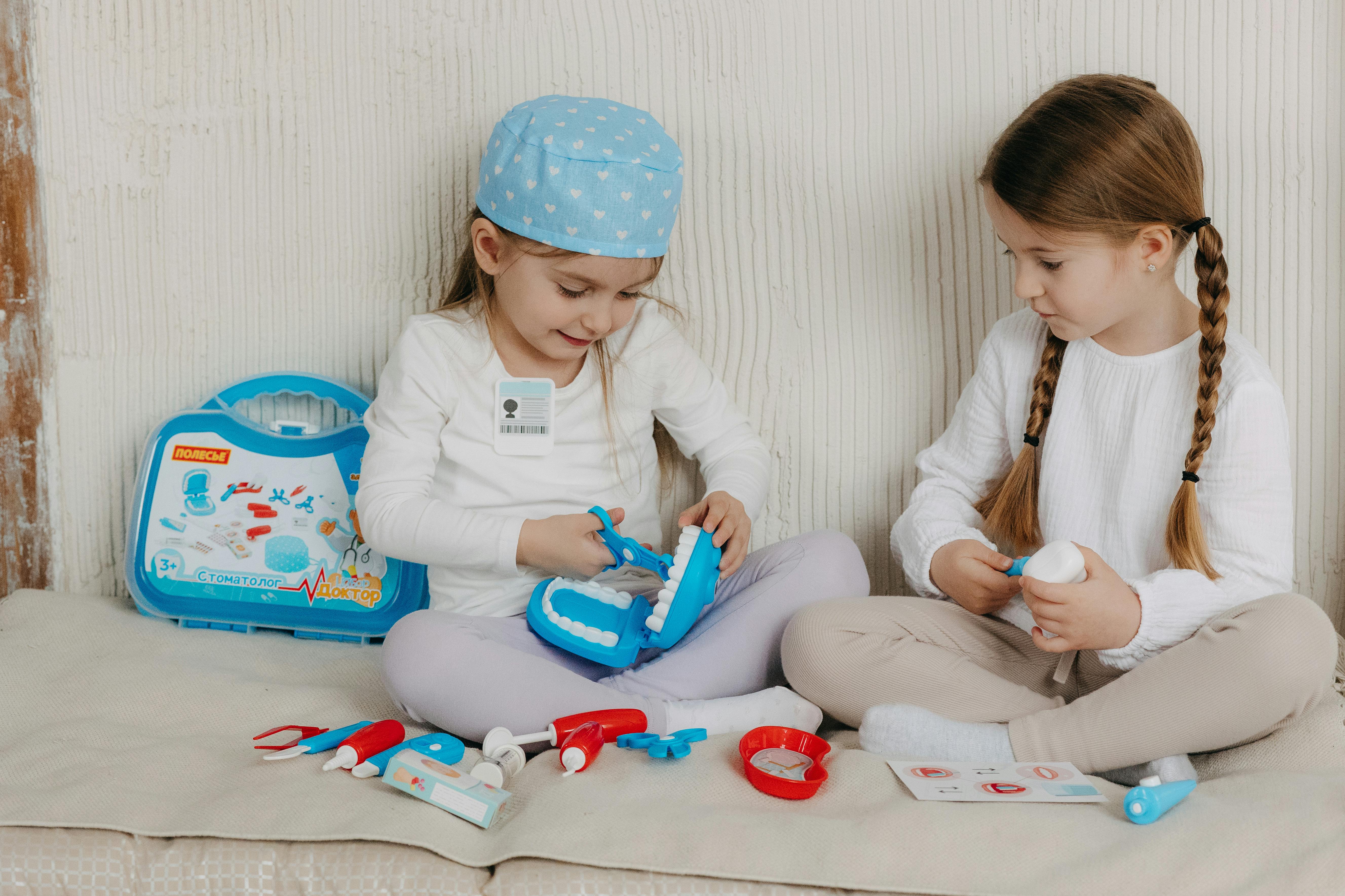 two little girls sitting on a couch with toys