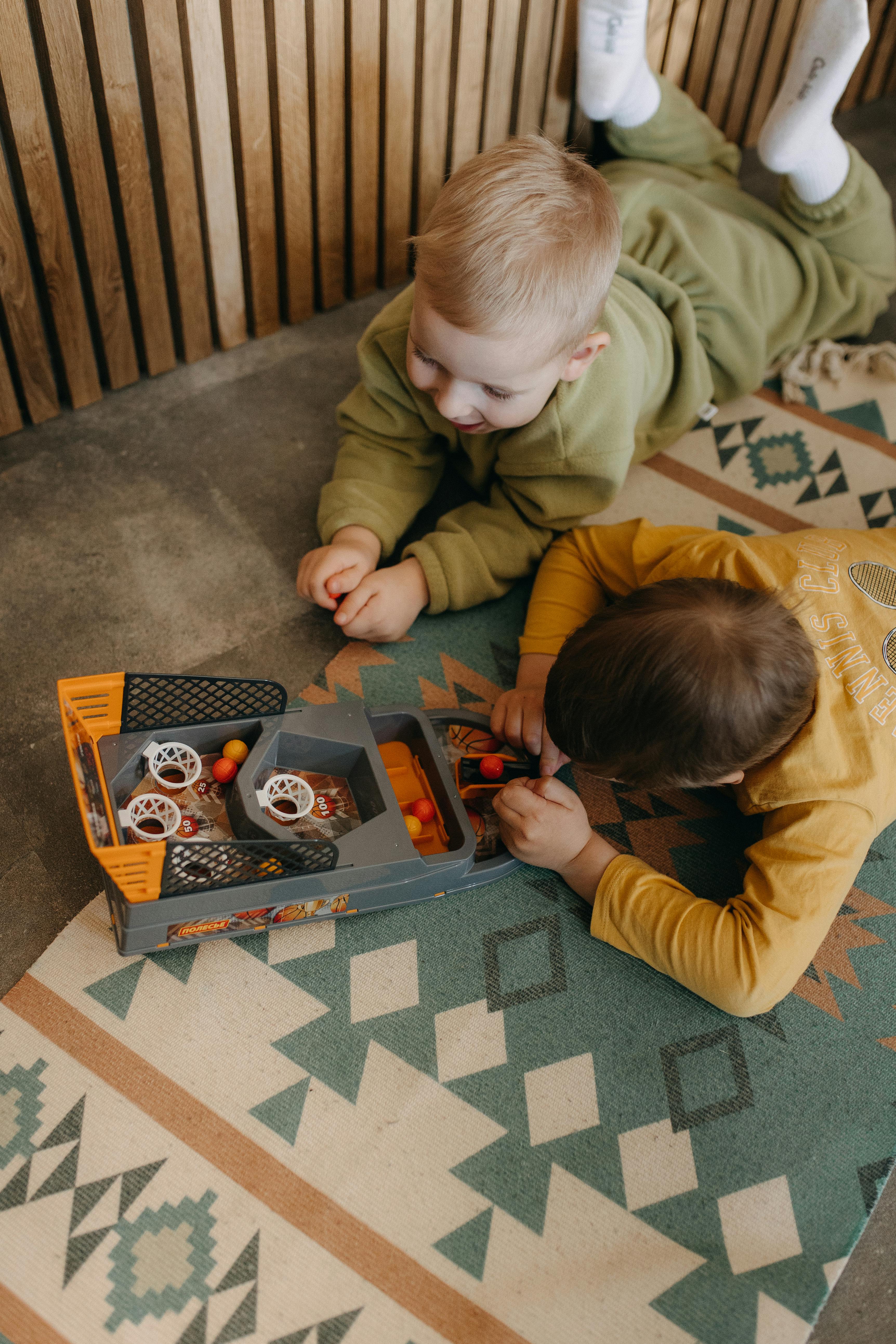 two children playing with toy cars on a rug