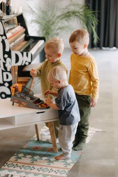 Three young kids enjoying a basketball toy indoors, showcasing playtime fun and sibling interaction.