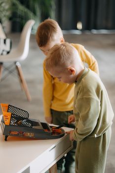 Two young boys enjoy playing with a toy basketball hoop indoors, capturing a moment of fun and togetherness.