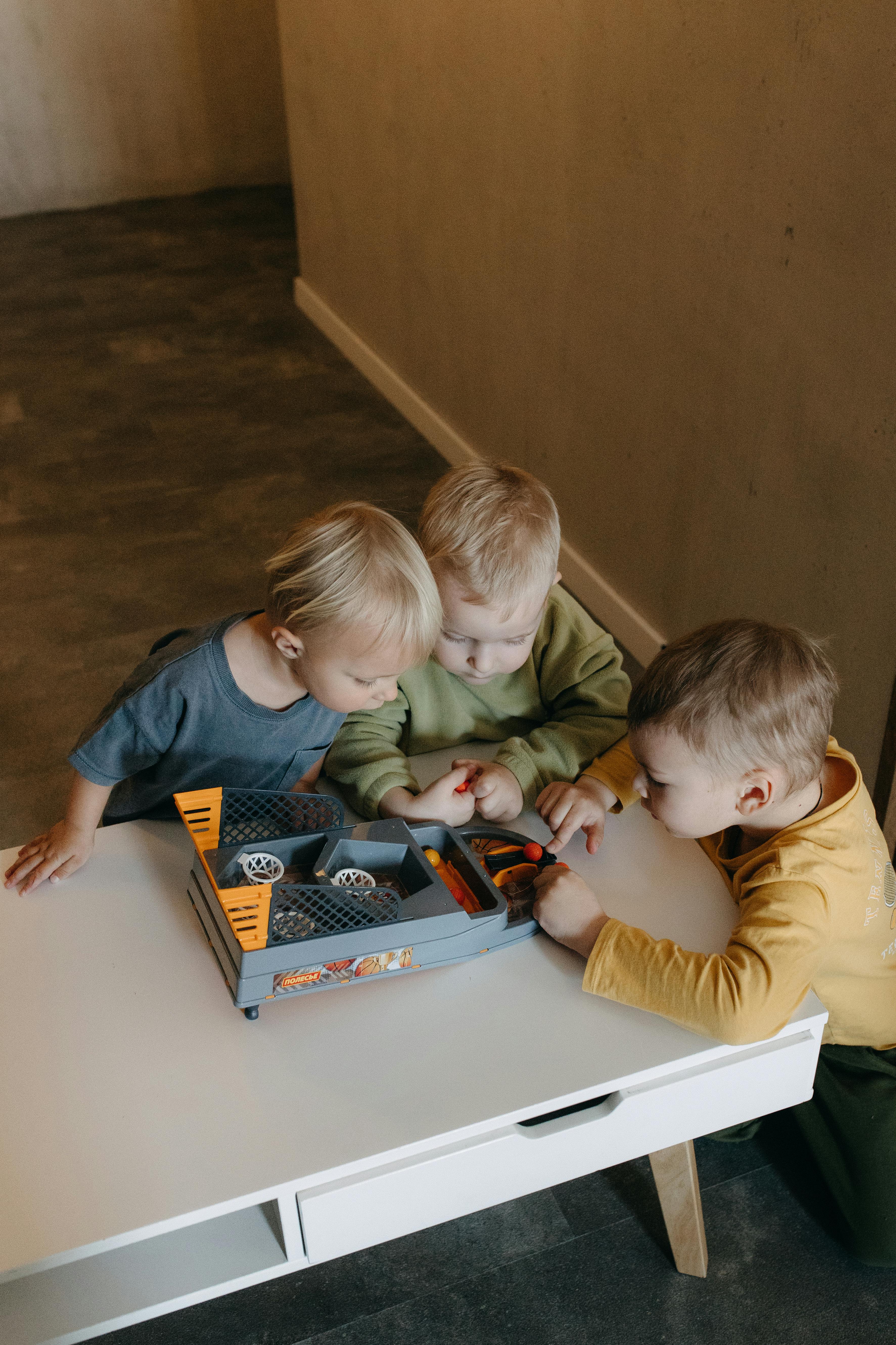 three children playing with a toy car on a table