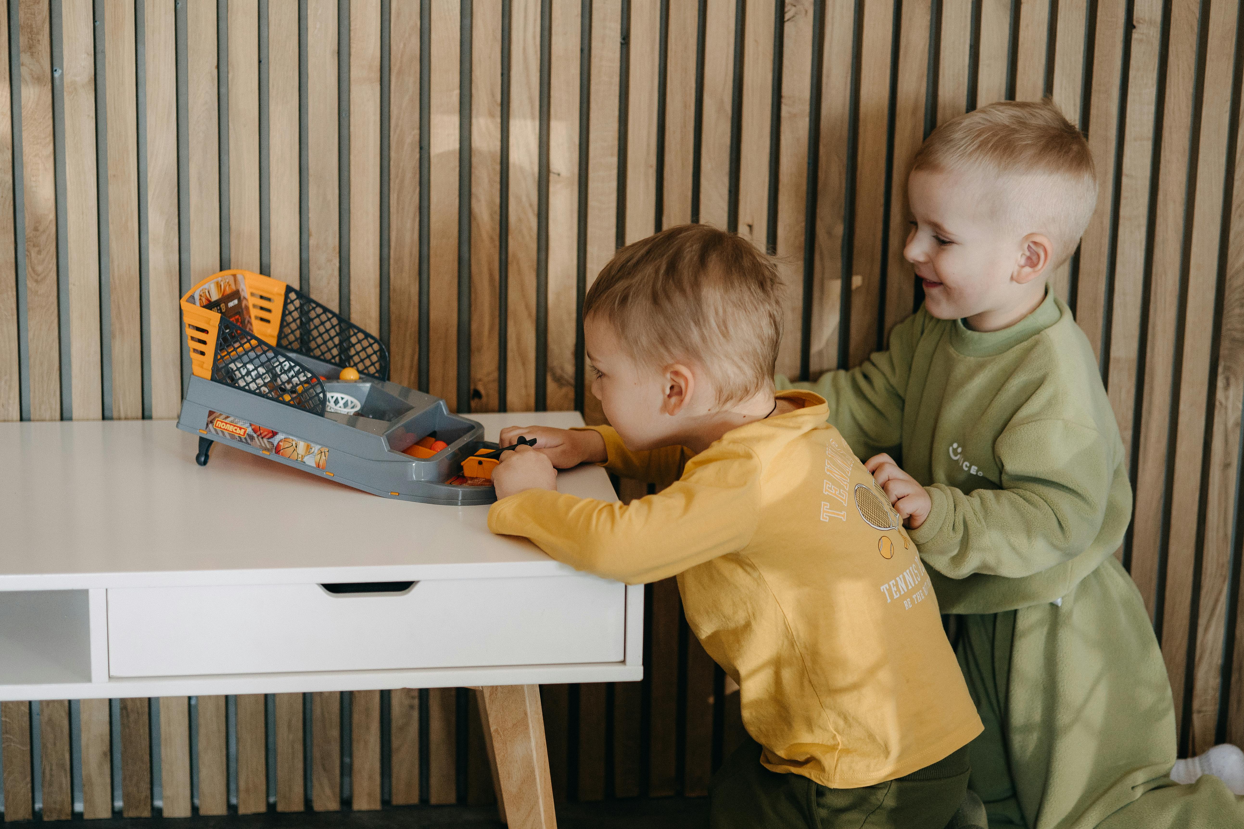 two children playing with a toy car on a table