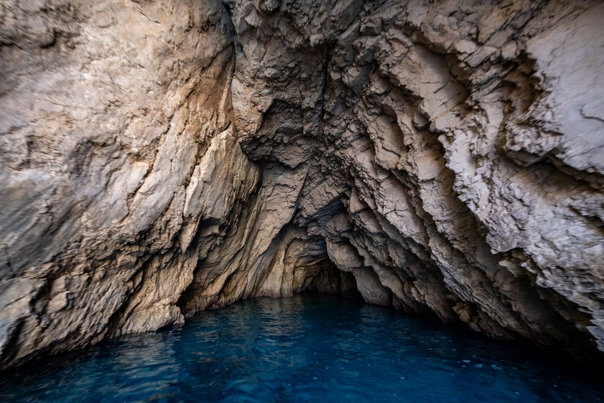 Dramatic limestone cave with stunning blue water reflecting light from below