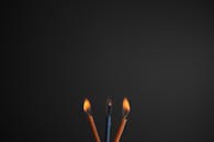 在黑暗背景的映衬下，三支燃烧蜡烛的特写营造出温暖而亲密的氛围