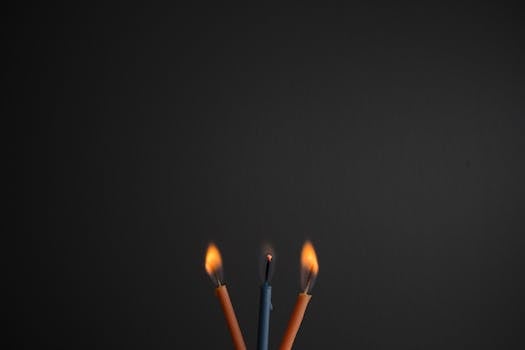 在黑暗背景的映衬下，三支燃烧蜡烛的特写营造出温暖而亲密的氛围