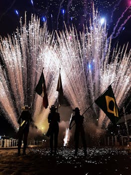 在五颜六色的烟花映照的夜空下，人们挥舞着旗帜，形成剪影