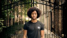 Photo of a Man Standing Beside Black Gate