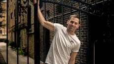 一个开朗的男人穿着休闲服装，在芝加哥小巷的铁门前摆出自信而有型的姿势