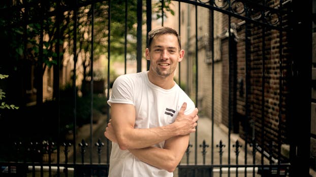 一个穿着休闲服的男人面带微笑，自信地在城市街道的铁门前摆着姿势