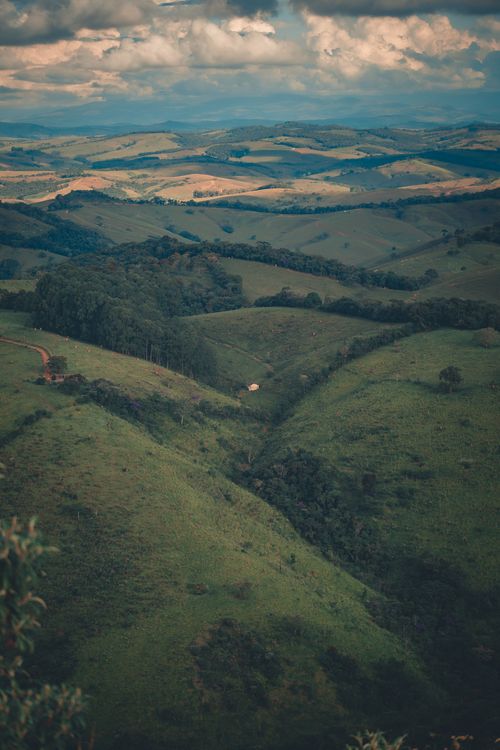 Free Tranquil landscape of green rolling hills under a cloudy sky, perfect for nature lovers. Stock Photo