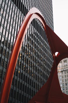 城市场景以现代玻璃建筑为特色，并配有醒目的红色雕塑