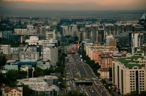 Free Stunning aerial view of Almaty's skyline with traffic and mountains in the background during sunset. Stock Photo