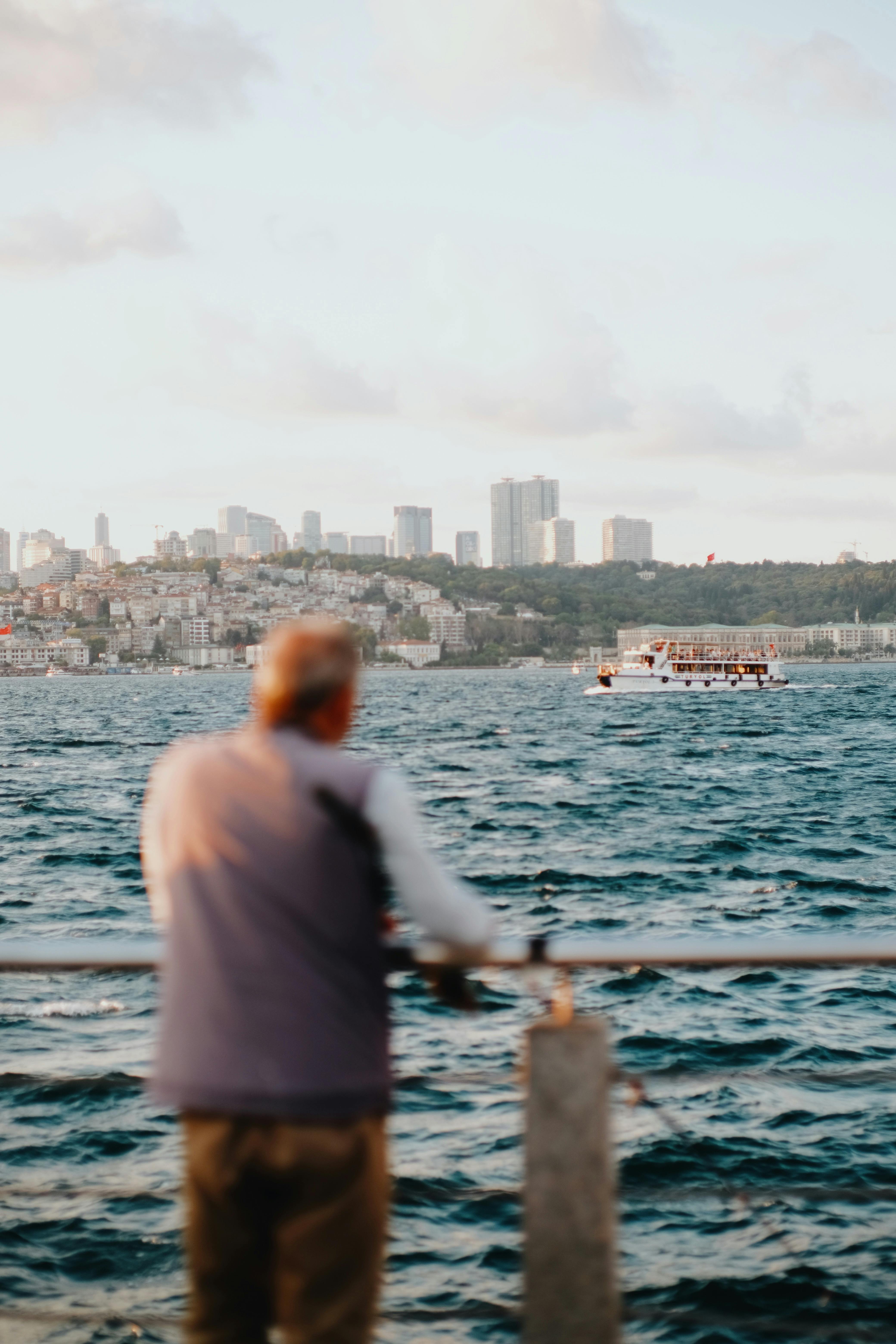 Free A man enjoys the serene view of the Bosphorus with Istanbul skyline at sunset. Stock Photo