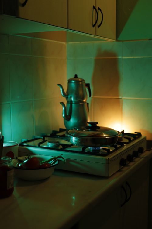 Free Warmly lit kitchen with a gas stove and classic teapot, creating a vintage atmosphere. Stock Photo