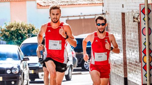 Free Two men in red outfits running in an urban marathon during the day. Stock Photo